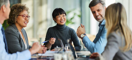 Group of people engaging in a meeting sitting around a table